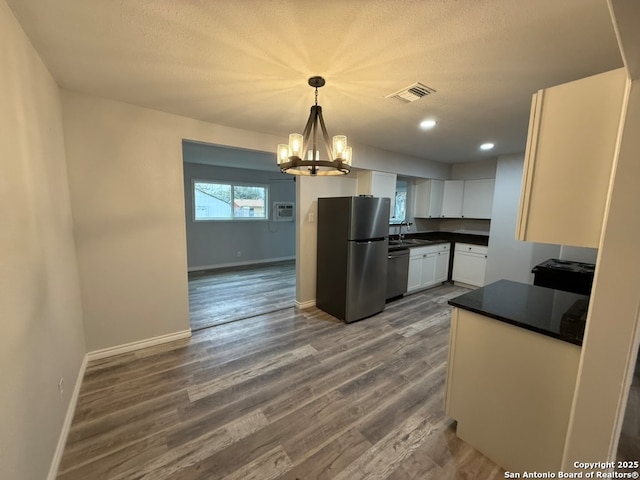 kitchen with sink, dark wood-type flooring, white cabinetry, stainless steel appliances, and decorative light fixtures