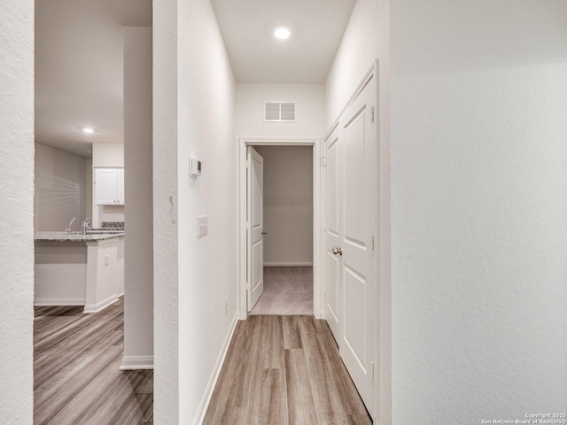 hallway featuring sink and light wood-type flooring