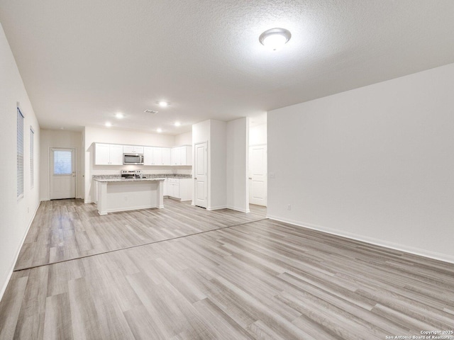 unfurnished living room featuring a textured ceiling and light wood-type flooring