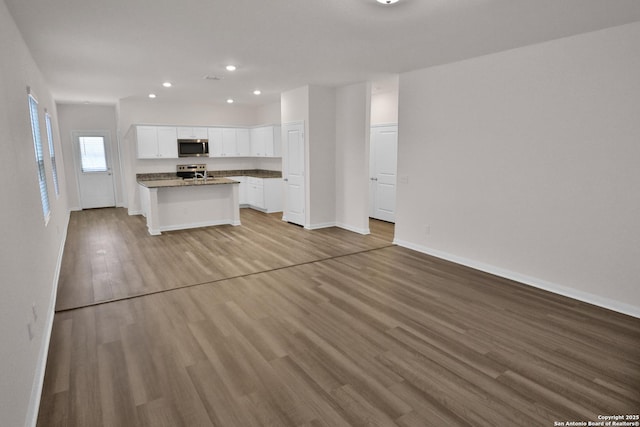 kitchen with light hardwood / wood-style flooring, a center island with sink, white cabinets, and appliances with stainless steel finishes