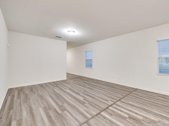 spare room featuring a textured ceiling and light wood-type flooring