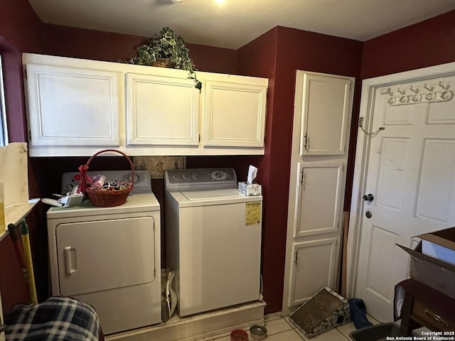 laundry room featuring washer and clothes dryer, cabinets, and light tile patterned flooring