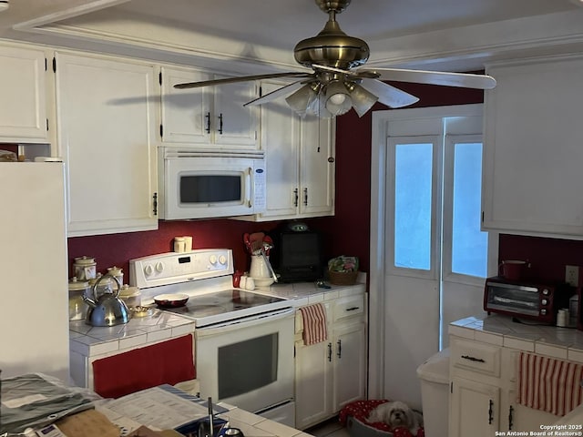 kitchen featuring white cabinetry, tile counters, ceiling fan, and white appliances