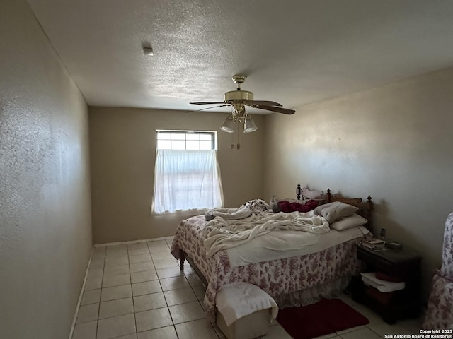 bedroom featuring ceiling fan, light tile patterned floors, and a textured ceiling