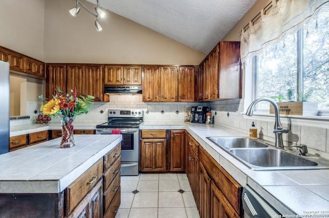 kitchen featuring stainless steel electric range oven, lofted ceiling, sink, and tile countertops