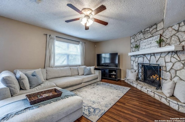 living room featuring dark wood-type flooring, a fireplace, a textured ceiling, and ceiling fan