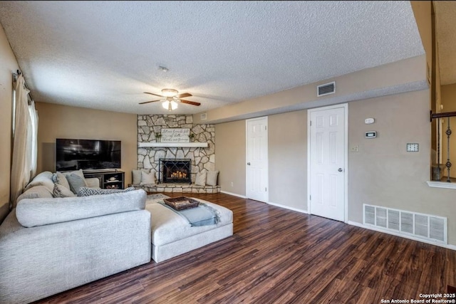 living room with hardwood / wood-style flooring, ceiling fan, a stone fireplace, and a textured ceiling