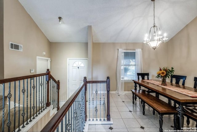 tiled dining area with an inviting chandelier, lofted ceiling, and a textured ceiling