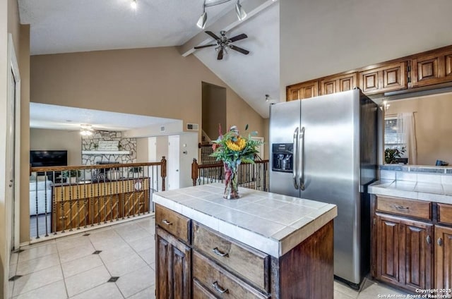 kitchen featuring a center island, tile countertops, ceiling fan, and stainless steel fridge with ice dispenser