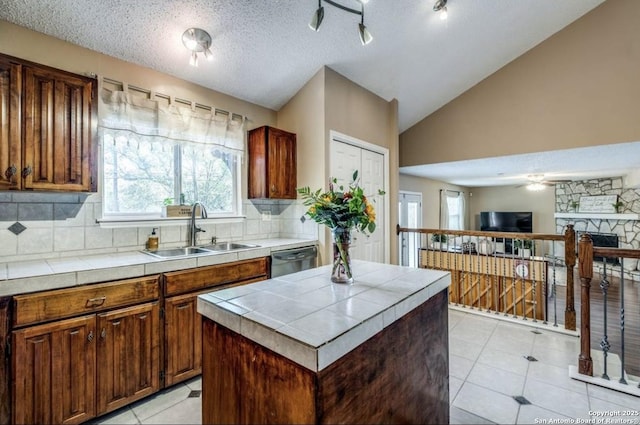 kitchen with sink, tile counters, a center island, and dishwasher