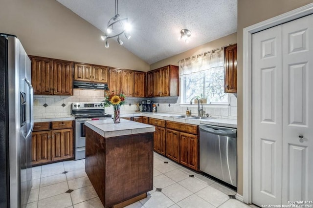 kitchen featuring vaulted ceiling, a kitchen island, sink, hanging light fixtures, and stainless steel appliances