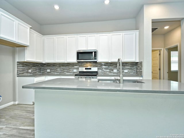 kitchen featuring sink, backsplash, stainless steel appliances, and white cabinets