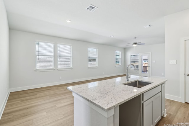 14603 Rainwater Trl, San Antonio, TX 78253 - kitchen featuring visible vents, baseboards, light stone countertops, a sink, and light wood-type flooring