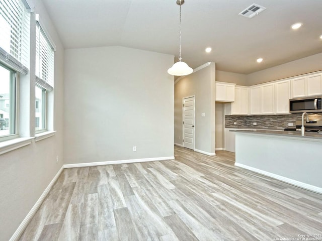 kitchen featuring light hardwood / wood-style flooring, range, white cabinetry, tasteful backsplash, and decorative light fixtures