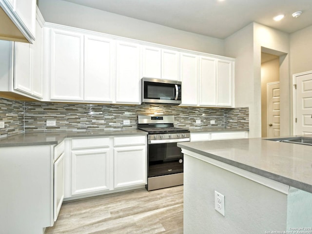 kitchen with tasteful backsplash, appliances with stainless steel finishes, and white cabinets