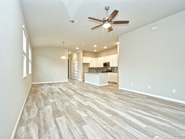 unfurnished living room with lofted ceiling, sink, light hardwood / wood-style flooring, and ceiling fan