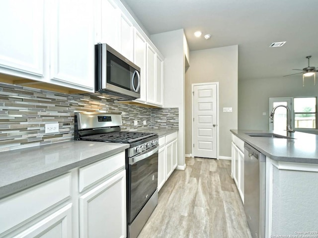 kitchen featuring white cabinetry, sink, decorative backsplash, stainless steel appliances, and light hardwood / wood-style flooring