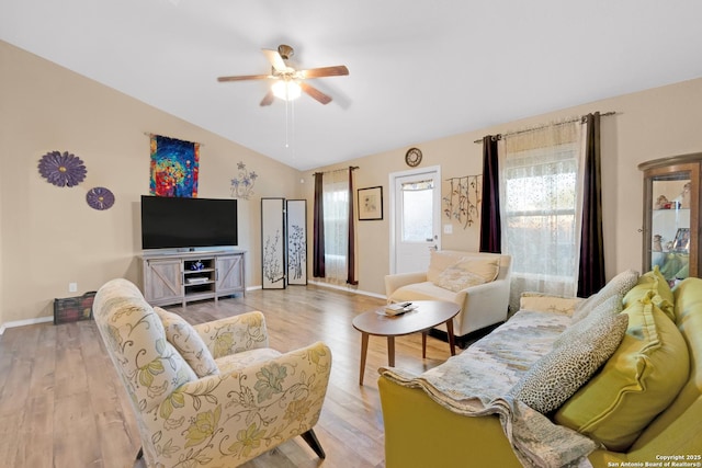 living room with ceiling fan, vaulted ceiling, and light wood-type flooring