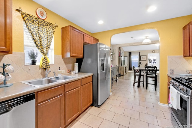 kitchen with sink, backsplash, light tile patterned floors, and appliances with stainless steel finishes