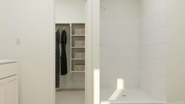 bathroom featuring tiled shower and vanity
