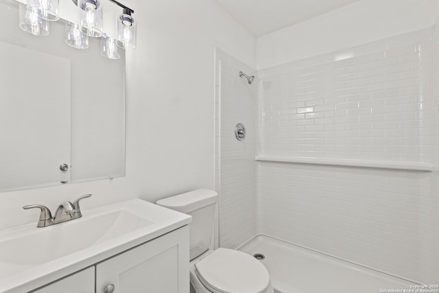 bathroom featuring a tile shower, vanity, and toilet