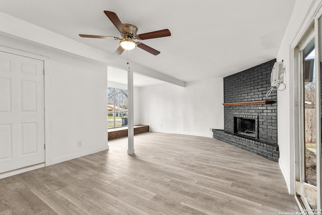 unfurnished living room featuring ceiling fan, a wall mounted air conditioner, a fireplace, and light hardwood / wood-style floors