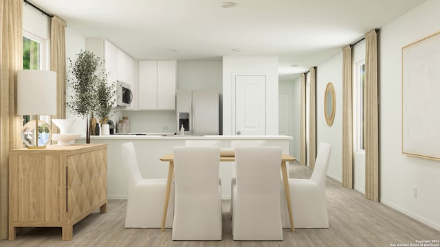 kitchen featuring appliances with stainless steel finishes, a breakfast bar area, light hardwood / wood-style flooring, and white cabinets