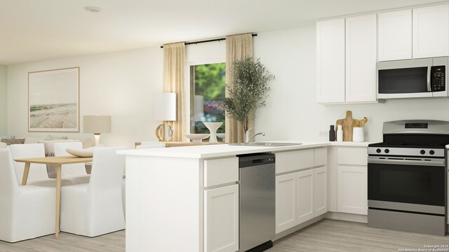 kitchen with appliances with stainless steel finishes, kitchen peninsula, sink, and white cabinets