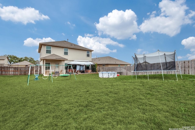 back of property featuring a playground, a trampoline, a yard, a fenced in pool, and a gazebo