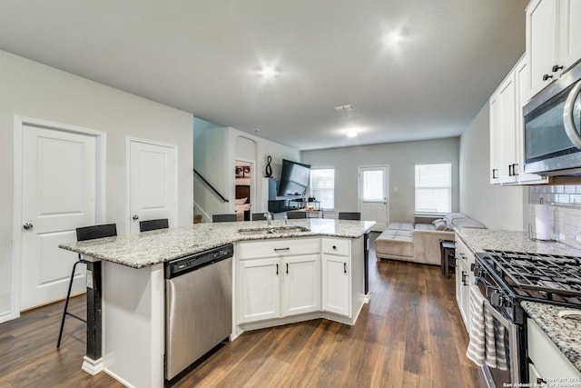 kitchen featuring appliances with stainless steel finishes, an island with sink, a breakfast bar area, and white cabinets