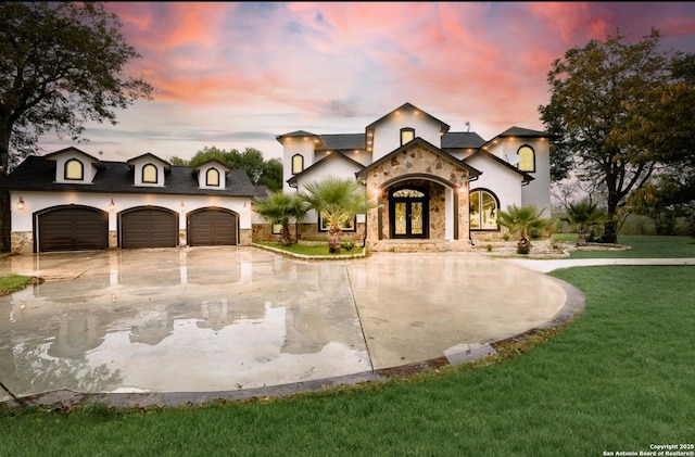 view of front of property with a garage, a lawn, and french doors