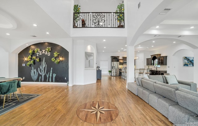 living room with hardwood / wood-style flooring, sink, and a high ceiling