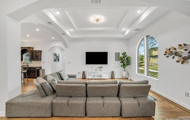 living room with light hardwood / wood-style floors and a tray ceiling