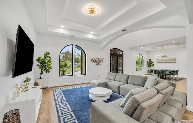 living room featuring hardwood / wood-style floors, a chandelier, and a tray ceiling