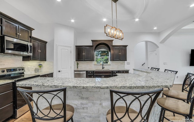 kitchen with sink, a breakfast bar area, hanging light fixtures, stainless steel appliances, and a spacious island