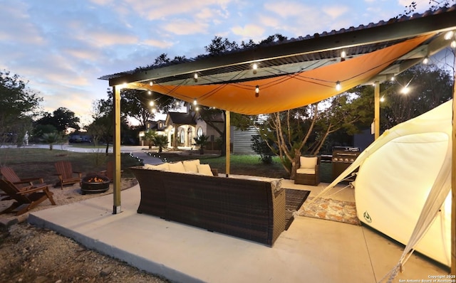 patio terrace at dusk featuring a grill and an outdoor living space with a fire pit