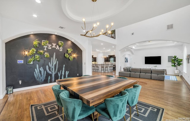 dining room featuring a raised ceiling, hardwood / wood-style floors, and a notable chandelier