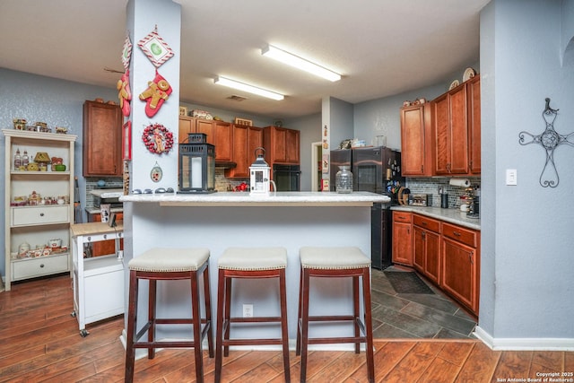 kitchen with stainless steel refrigerator, an island with sink, a breakfast bar area, dark hardwood / wood-style flooring, and decorative backsplash