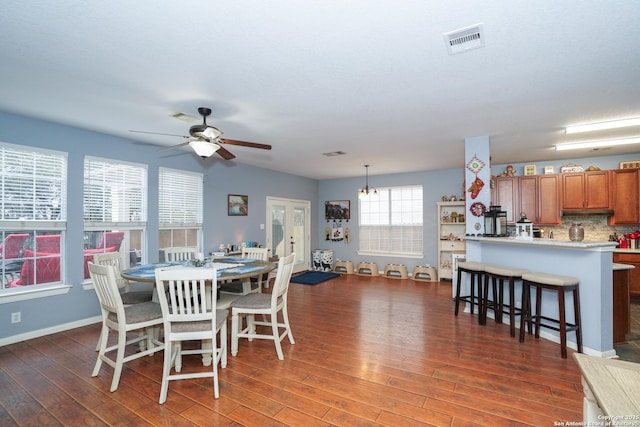 dining space with dark wood-type flooring and ceiling fan with notable chandelier