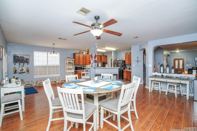 dining area with dark hardwood / wood-style floors and ceiling fan with notable chandelier