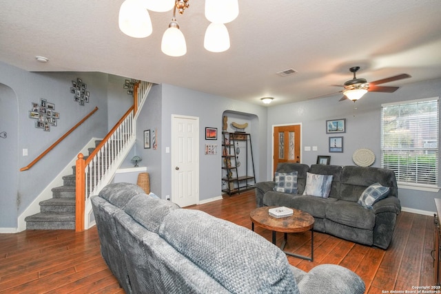 living room featuring dark hardwood / wood-style floors, ceiling fan with notable chandelier, and a textured ceiling