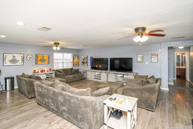 living room featuring ceiling fan, a textured ceiling, and light hardwood / wood-style flooring