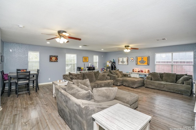 living room with a wealth of natural light, ceiling fan, and light wood-type flooring