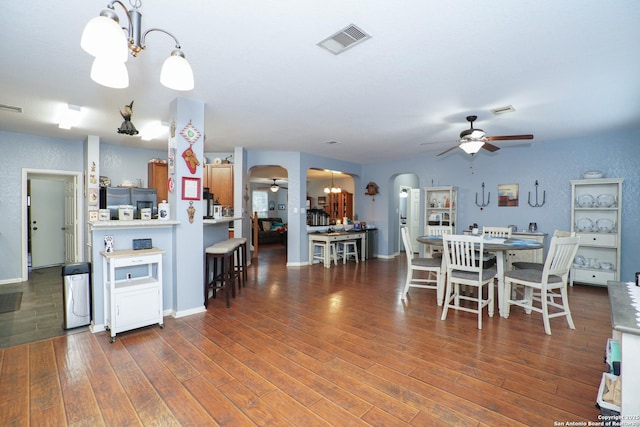 dining area with ceiling fan with notable chandelier and dark hardwood / wood-style flooring