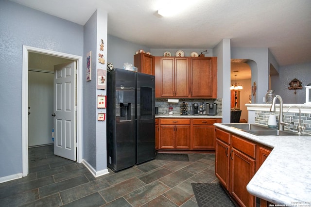 kitchen with a notable chandelier, stainless steel refrigerator with ice dispenser, sink, and backsplash