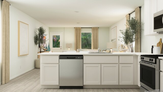 kitchen with stainless steel appliances, white cabinetry, sink, and light hardwood / wood-style flooring