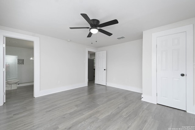 unfurnished bedroom with ceiling fan, ensuite bath, and light hardwood / wood-style floors