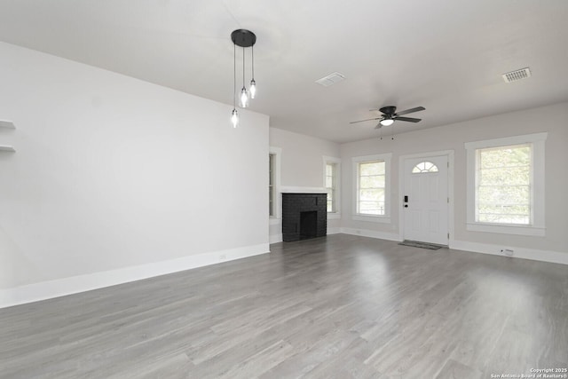 unfurnished living room with wood-type flooring, ceiling fan, and a fireplace