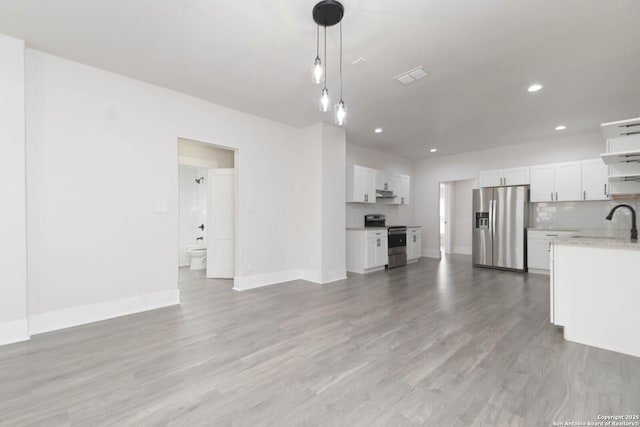 kitchen featuring pendant lighting, backsplash, stainless steel appliances, white cabinets, and light wood-type flooring