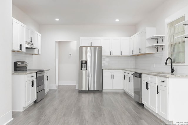 kitchen featuring sink, light hardwood / wood-style flooring, appliances with stainless steel finishes, light stone countertops, and white cabinets